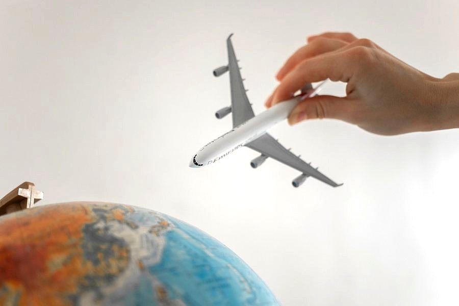A model aeroplane held above a globe, representing international holiday planning